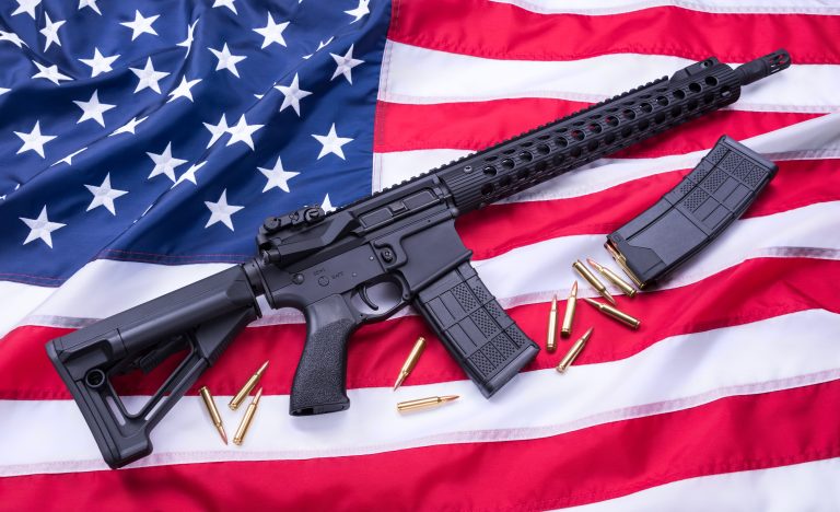 Custom built AR-15 carbine, bullets and a magazine on American flag surface, background. Studio shot.