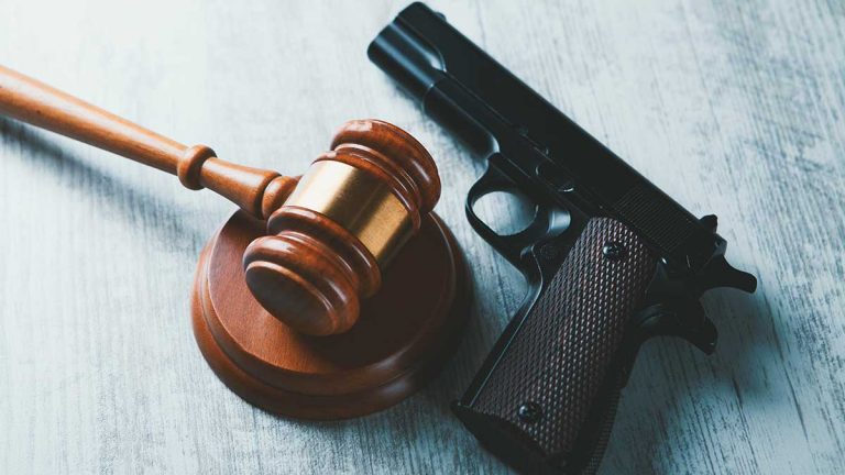 Image of a judge's gavel and a gun