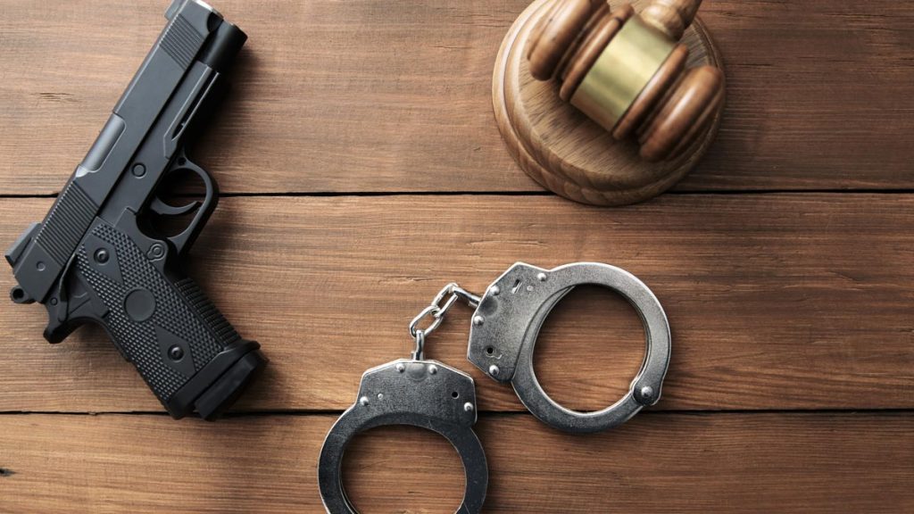 An image of a gun, handcuffs, and a judge's gavel.