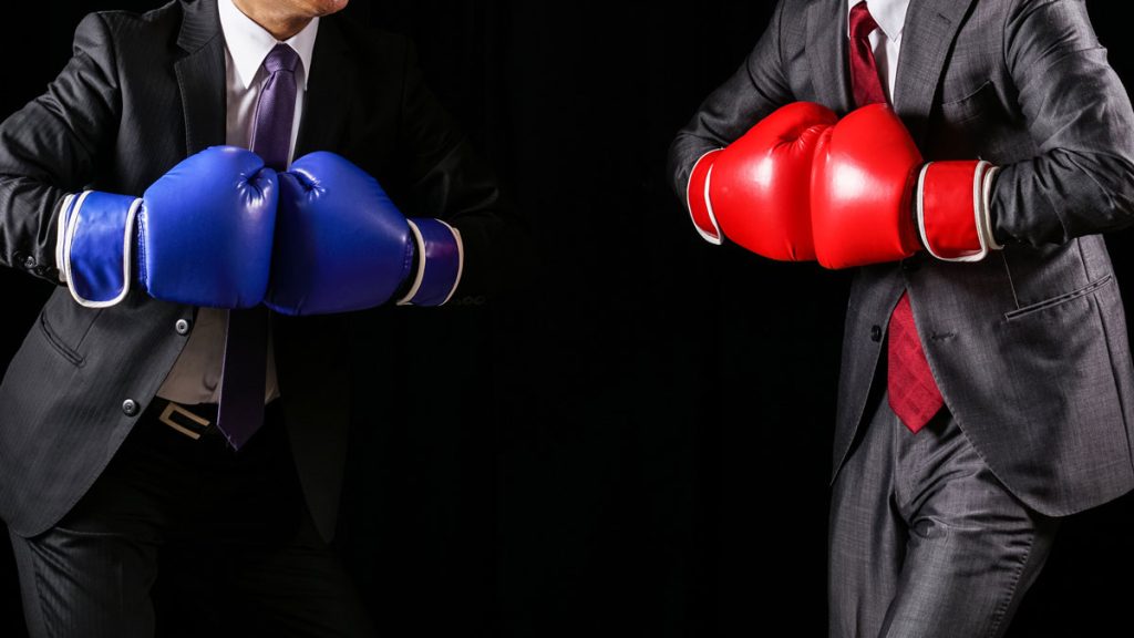 Men in suits wearing red and blue boxing gloves.