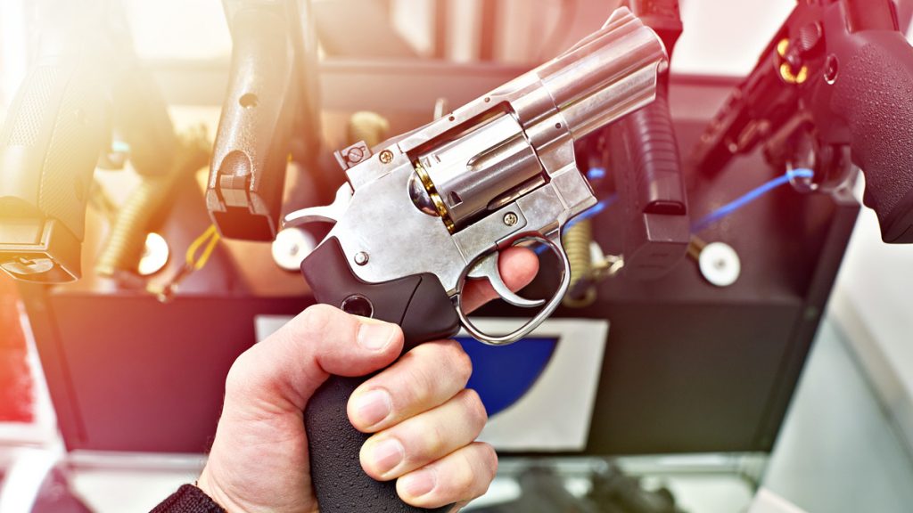 A person's hand holding a revolver in a gun shop