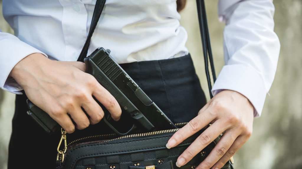 A woman putting her lawfully carried gun in her purse