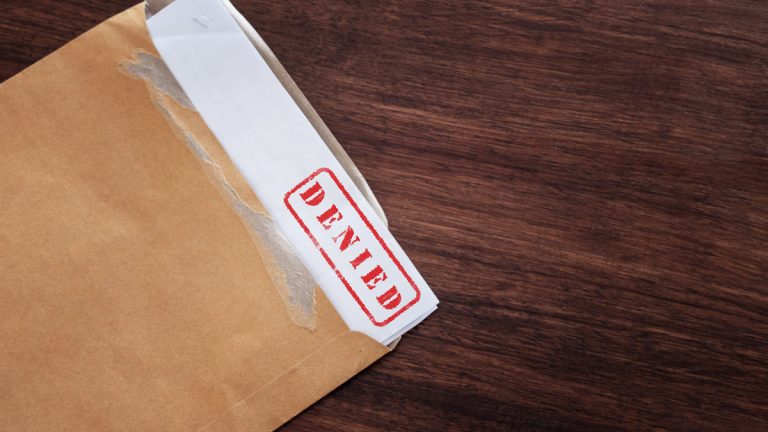 An envelope with a paper that says Denied