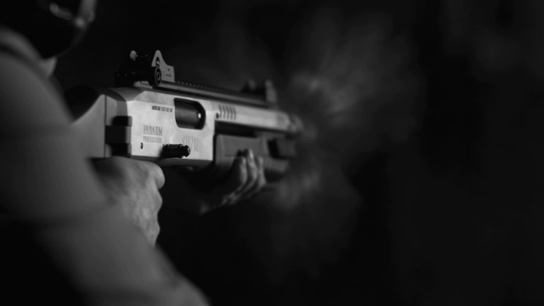 A person shooting a semiauto shotgun with a pistol grip