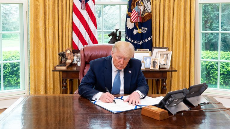 President Donald Trump signing a bill into law in the Oval Office.