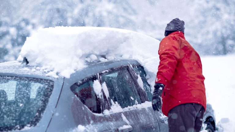 A person cleaning snow off their car